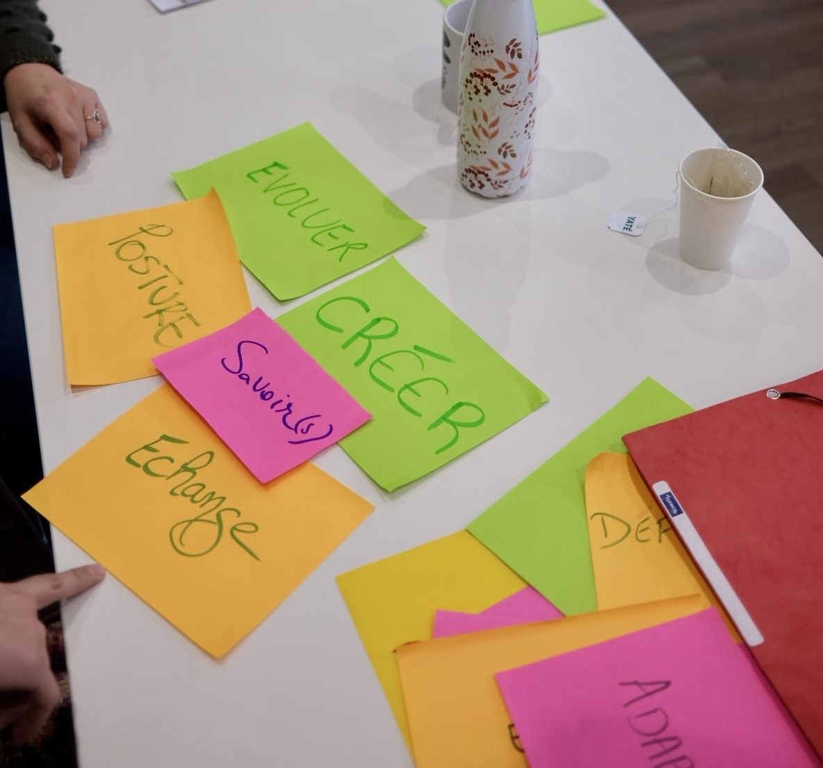 Post-its manuscrits posés sur une table portant les mots posture, évoluer, créer, échange, savoir(s)