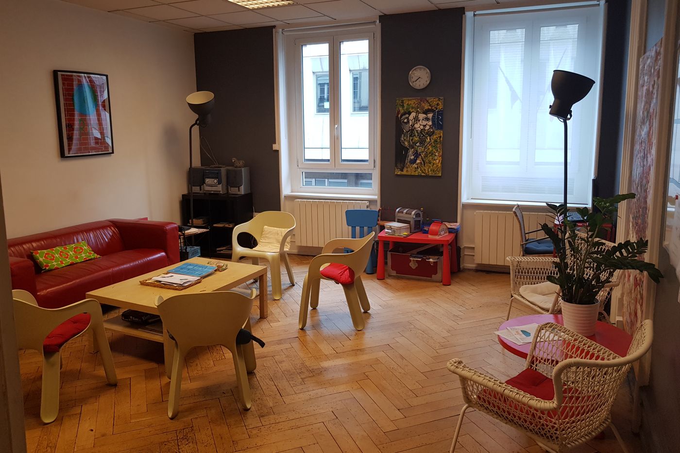 La salle d’attente du CSAPA, au 1er étage du 12 rue Kuhn : canapé rouge, chaises, table basse et coin enfants